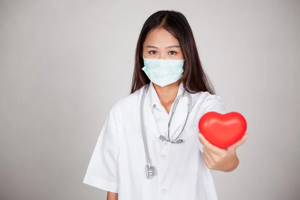 Giovane medico femminile asiatico con maschera e cuore rosso — Foto Stock