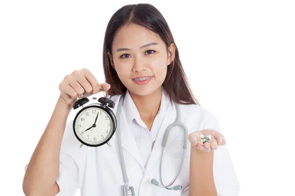 Joven asiática médico feliz mostrar un reloj y pastillas —  Fotos de Stock
