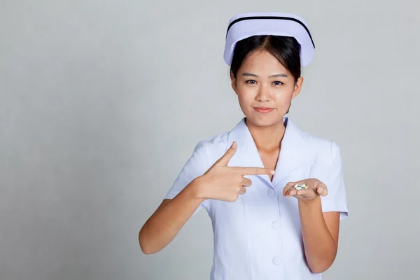 Jeune infirmière asiatique pointent vers des pilules sur sa main de la paume — Photo