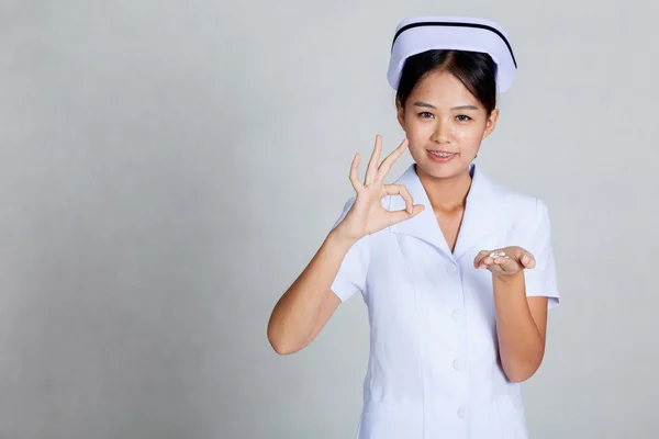 Junge asiatische Krankenschwester zeigen ok mit Pillen auf Ihre Handfläche Hand — Stockfoto