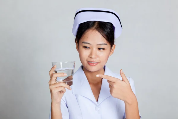 Junge asiatische Krankenschwester zeigen auf ein Glas Wasser — Stockfoto