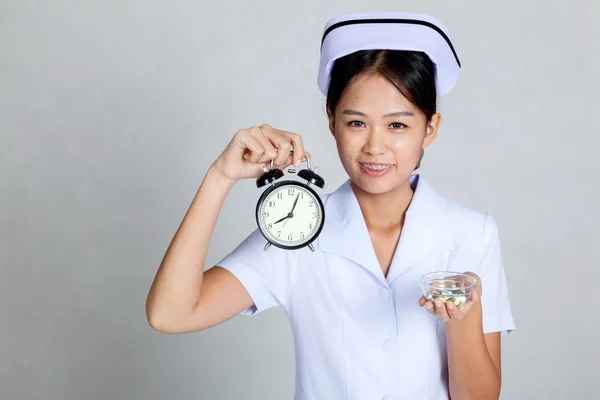 Junge asiatische Krankenschwester mit Uhr und Pillen auf ihrer Handfläche Hand — Stockfoto