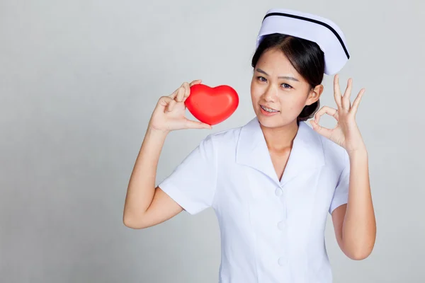 Junge asiatische Krankenschwester zeigen ok mit roten Herzen — Stockfoto