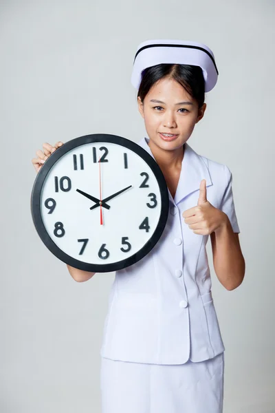 Asian young nurse show thumbs up with a clock — Stock Photo, Image