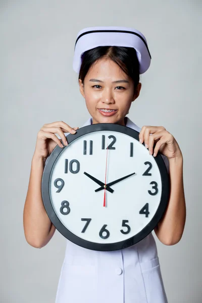 Asiatisk ung sygeplejeske smil med et ur - Stock-foto