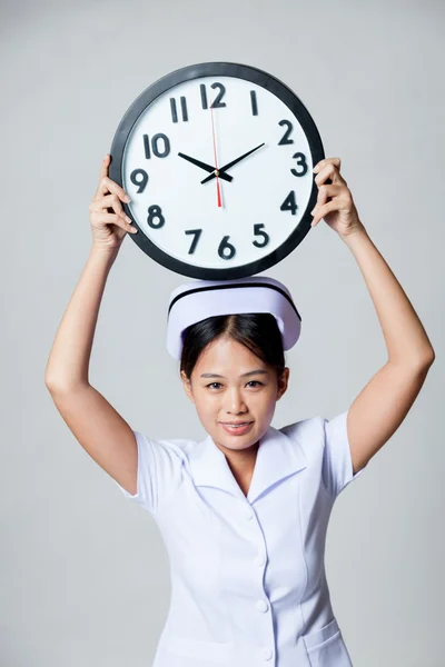 Jonge Aziatische verpleegkundige een klok weergeven over haar hoofd — Stockfoto