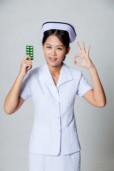 Junge asiatische Krankenschwester zeigen ok mit Packung Tablette — Stockfoto