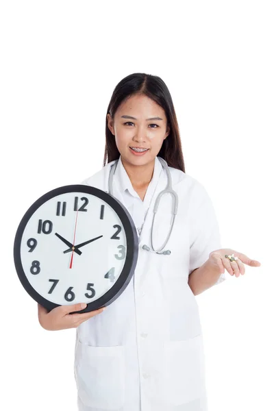 Junge asiatische Ärztin lächelt mit einer Uhr und Pillen in der Hand — Stockfoto