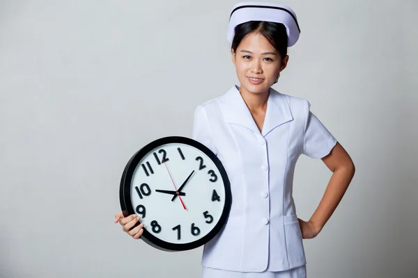 Young Asian nurse with clock — Stock Photo, Image