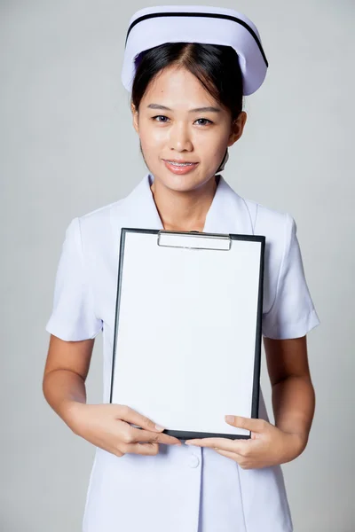 Junge asiatische Krankenschwester zeigen leeres Papier auf Klemmbrett — Stockfoto