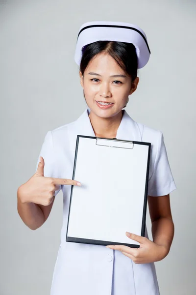 Junge asiatische Krankenschwester zeigen auf leeres Papier auf Klemmbrett — Stockfoto