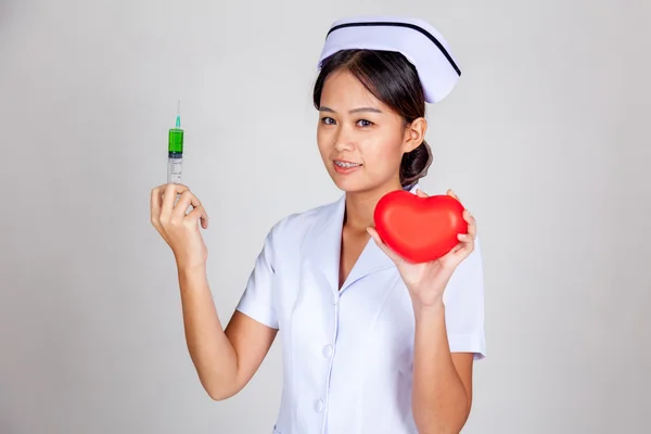 Giovane infermiera asiatica tenere siringa e cuore rosso — Foto Stock