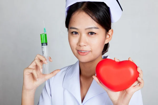 Junge asiatische Krankenschwester halten Spritze und rotes Herz — Stockfoto