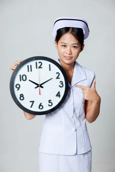 Asian young nurse point to a clock — Stock Photo, Image