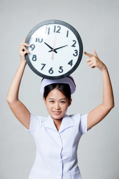 Joven asiática enfermera punto a reloj sobre su cabeza — Foto de Stock