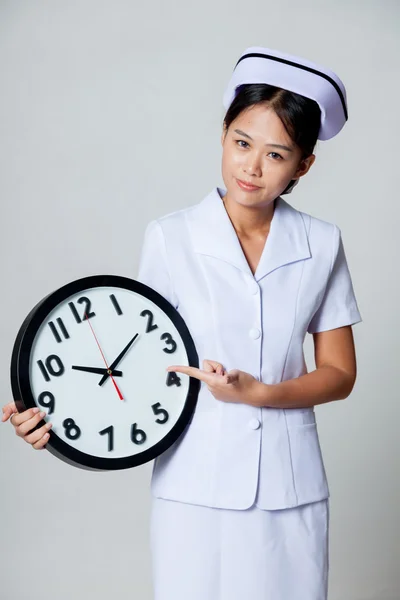 Young Asian nurse point to a clock — Stock Photo, Image