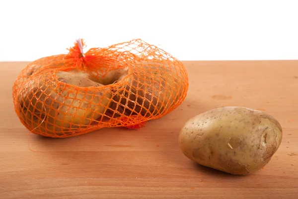 Potatoes in bag on wooden table — Stock Photo, Image