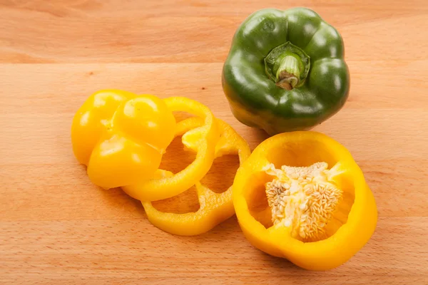 Cut yellow and green bell peppers on cutting board — Stock Photo, Image