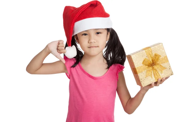 Pequeña chica asiática con sombrero de santa y caja de regalo pulgares abajo — Foto de Stock