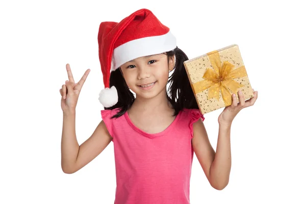 Kleine asiatische Mädchen mit Weihnachtsmann Hut und Geschenkbox zeigen 2 Finger Stockbild