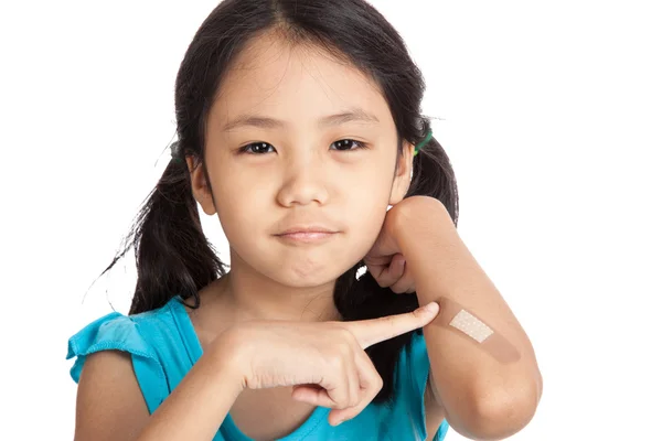 Kleine asiatische Mädchen zeigen auf Verband auf ihrem Arm — Stockfoto