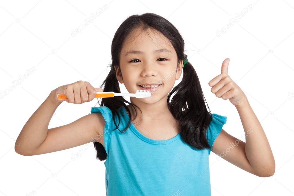 Little asian girl thumbs up with toothbrush