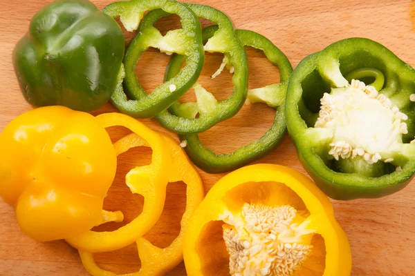 Cortar pimientos amarillos y verdes en la tabla de cortar — Foto de Stock