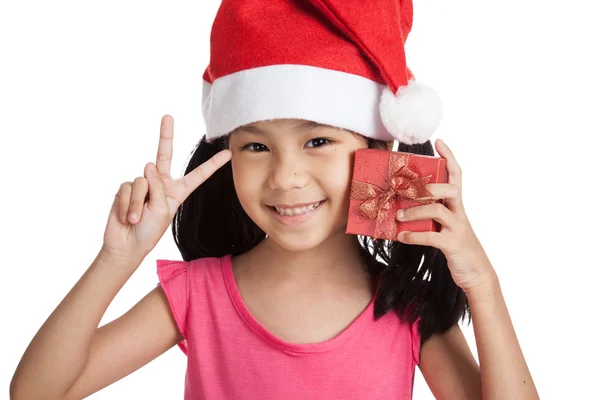 Happy little asian girl show victory sign with santa hat and gif — Zdjęcie stockowe