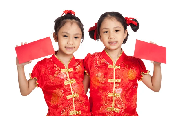 Asiático gêmeos meninas em chinês cheongsam vestido com envelopes vermelhos — Fotografia de Stock