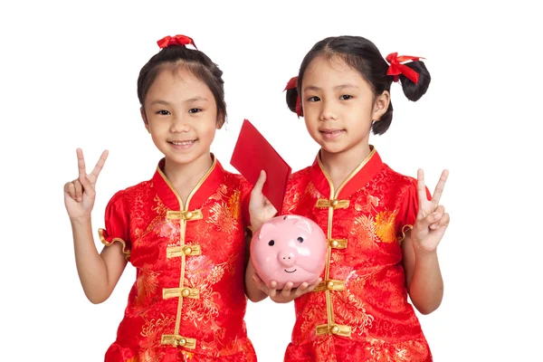 Asiatico gemelli ragazze in cinese cheongsam vestito con moneta banca e — Foto Stock