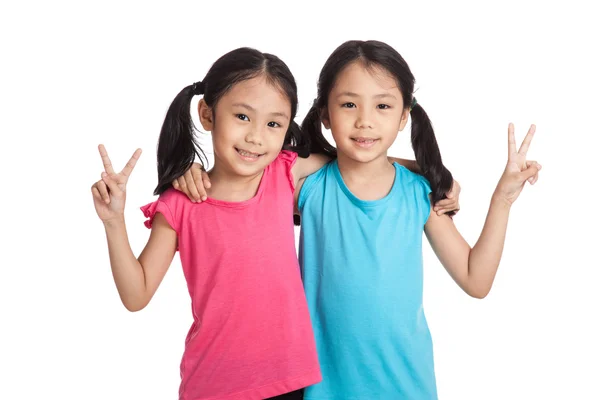 Счастливые азиатские близнецы девушки улыбаются знак победы — стоковое фото