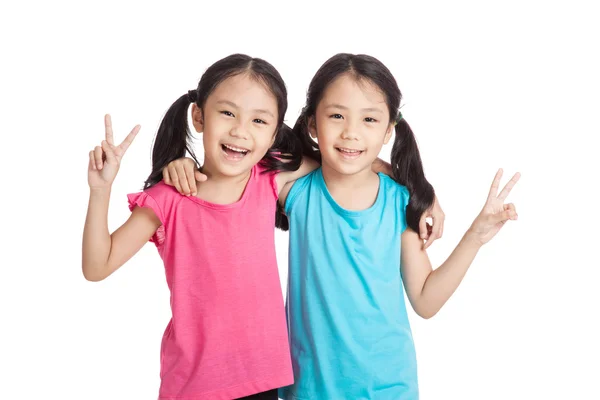 Счастливые азиатские близнецы девушки улыбаются знак победы — стоковое фото