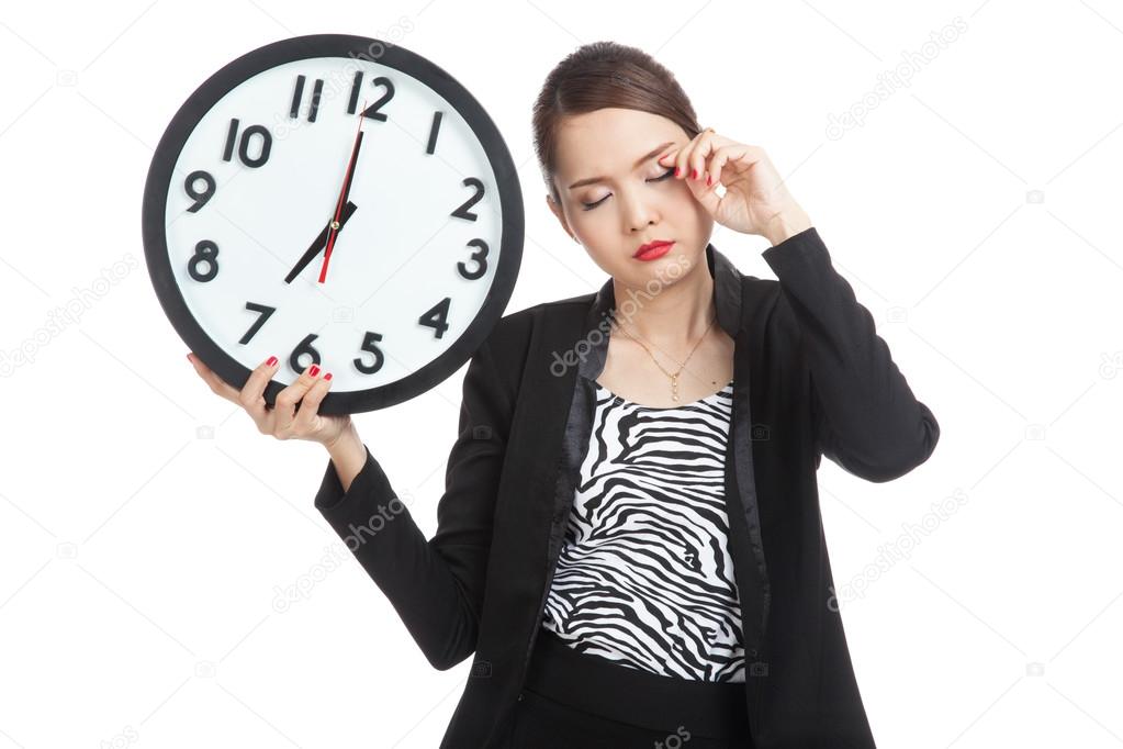 Sleepy young Asian business woman with a clock in the morning