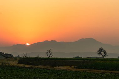Hindistan 'daki Jawai bandından siluet olarak görülen Aravalli dağlarının arkasından dinamik aralıklarla yükselen bir görüntü