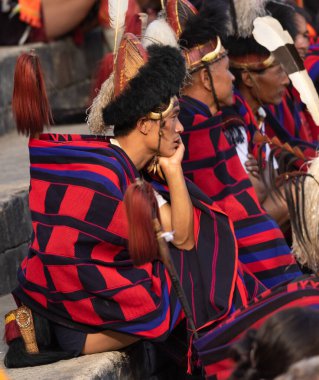 Selective focus image of Naga tribesmen wearing their traditional attire and siting together in Kisama heritage Village arena in Nagaland India on 4 December 2016