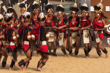 Selective focus image of a group of naga tribesmen dressed in their traditional attire performing a traditional activity while dancing during Hornbill festival in Nagaland India on 4 December 2016