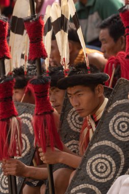 3 Aralık 2016 'da Hindistan' ın Nagaland kentindeki Kisama Heritage köyünde renkli giysiler içinde oturan ve baş vitesli genç Naga 'nın seçici odak görüntüsü