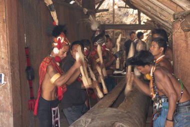 Selective focus with motion and movement image of Naga men hiting a wooden log with wood at Kisama village in Nagaland India on 2 December 2016