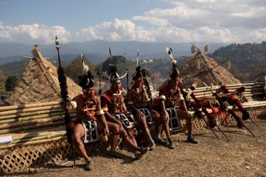 2 Aralık 2016 'da Nagaland Hindistan' daki Kisama köyünde geleneksel naga kulübesinde oturan ve dinlenen bir grup Naga savaşçısının seçici odak noktası.