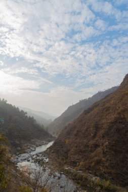 Dağların arasından akan bir akarsu bulutların içinde gökyüzünde bir desen oluşturuyor.
