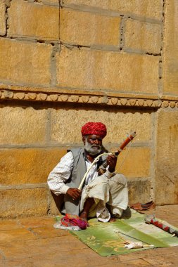 Türban takan bir adam 21 Şubat 2018 'de Jaiselmer Rajasthan Hindistan' da yerde oturuyor ve vilolin oynuyor.
