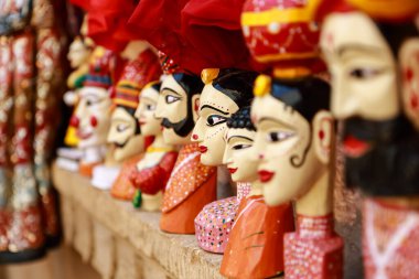 Hindistan 'ın Rajasthan şehrinde 21 Şubat 2018' de duvarlara asılı renkli kıyafetler giyen kuklalar şeklinde renkli insan yüzü.