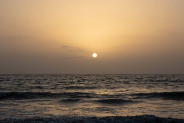 Ufuktan batan güneş manzarası ve okyanustan gelen dalgalar.