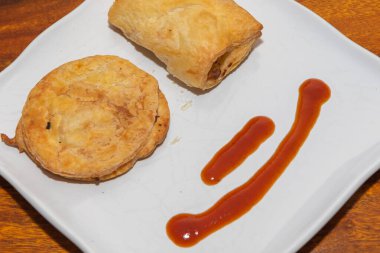 Beyaz bir tabakta domates sosuyla servis edilen fırında pişmiş börekler de denir.