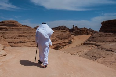 Saudian walking on top of rock formations, Saudi Arabia clipart
