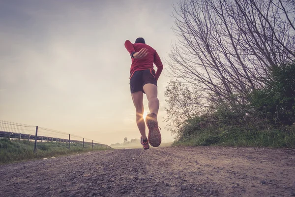 Un uomo che corre in campagna la mattina presto — Foto Stock