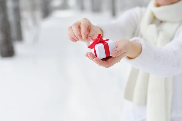 Closeup woman holds in his hands the gift and begins to open it.