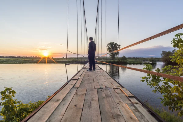 Людина на підвісному мосту — стокове фото