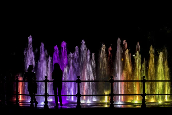 Meninas olhando para uma fonte colorida — Fotografia de Stock