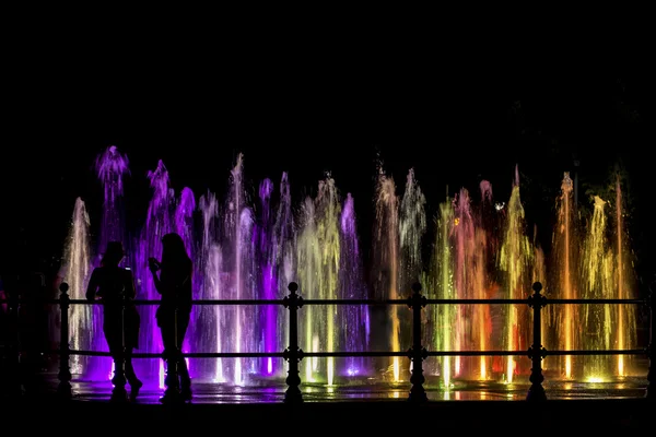 Ragazze guardando una fontana colorata — Foto Stock